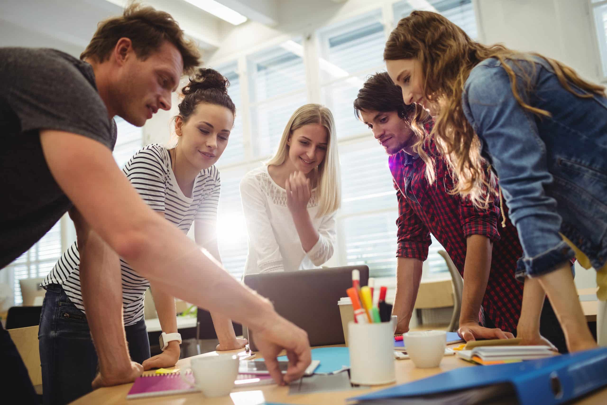 Graduação ead: Cinco pessoas ao redor de uma mesa trocando ideias criativas.