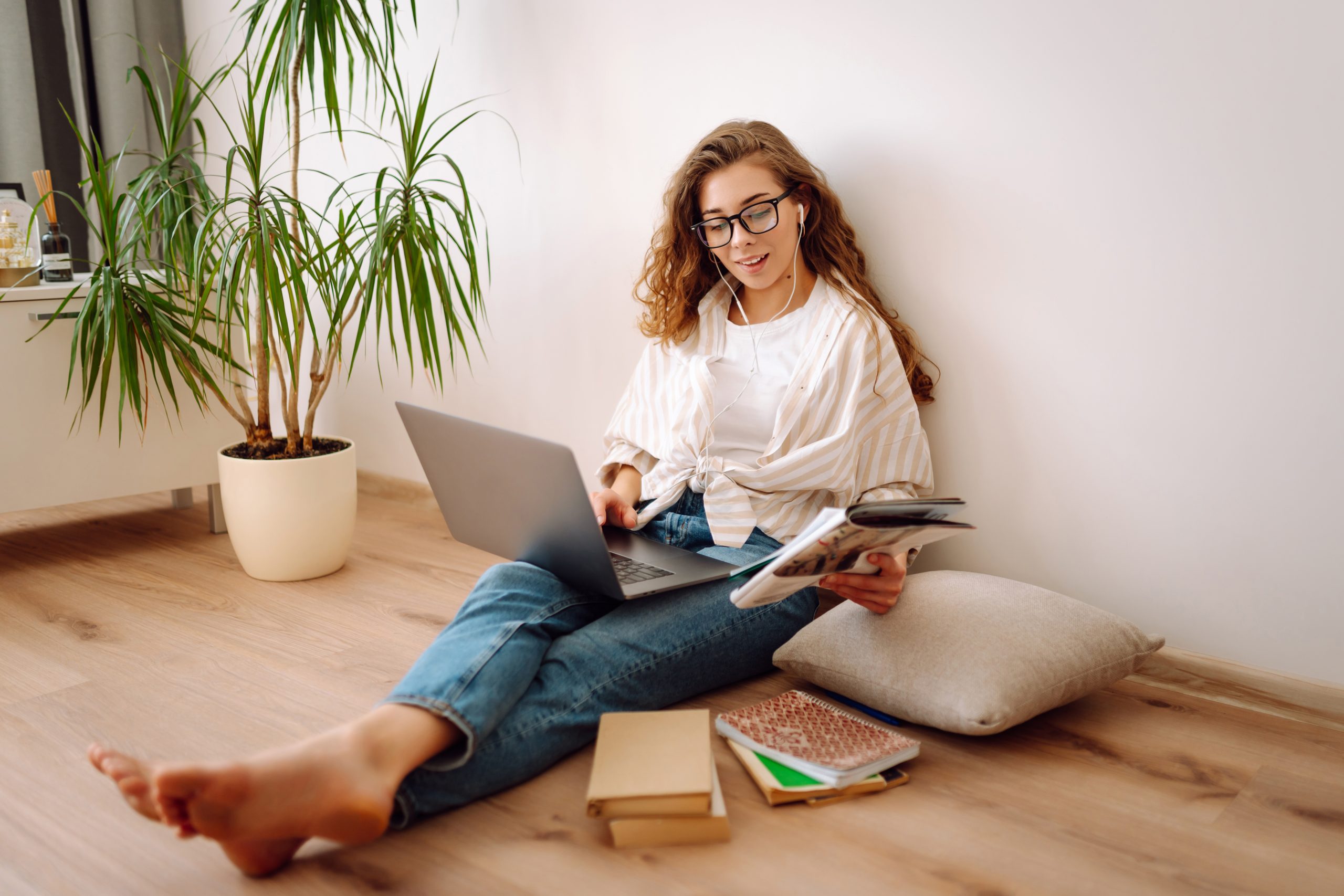 Diferença de especialização e pós-graduação: mulher sentada no chão com um notebook no colo, analisando as duas opções, especialização ou pós-graduação
