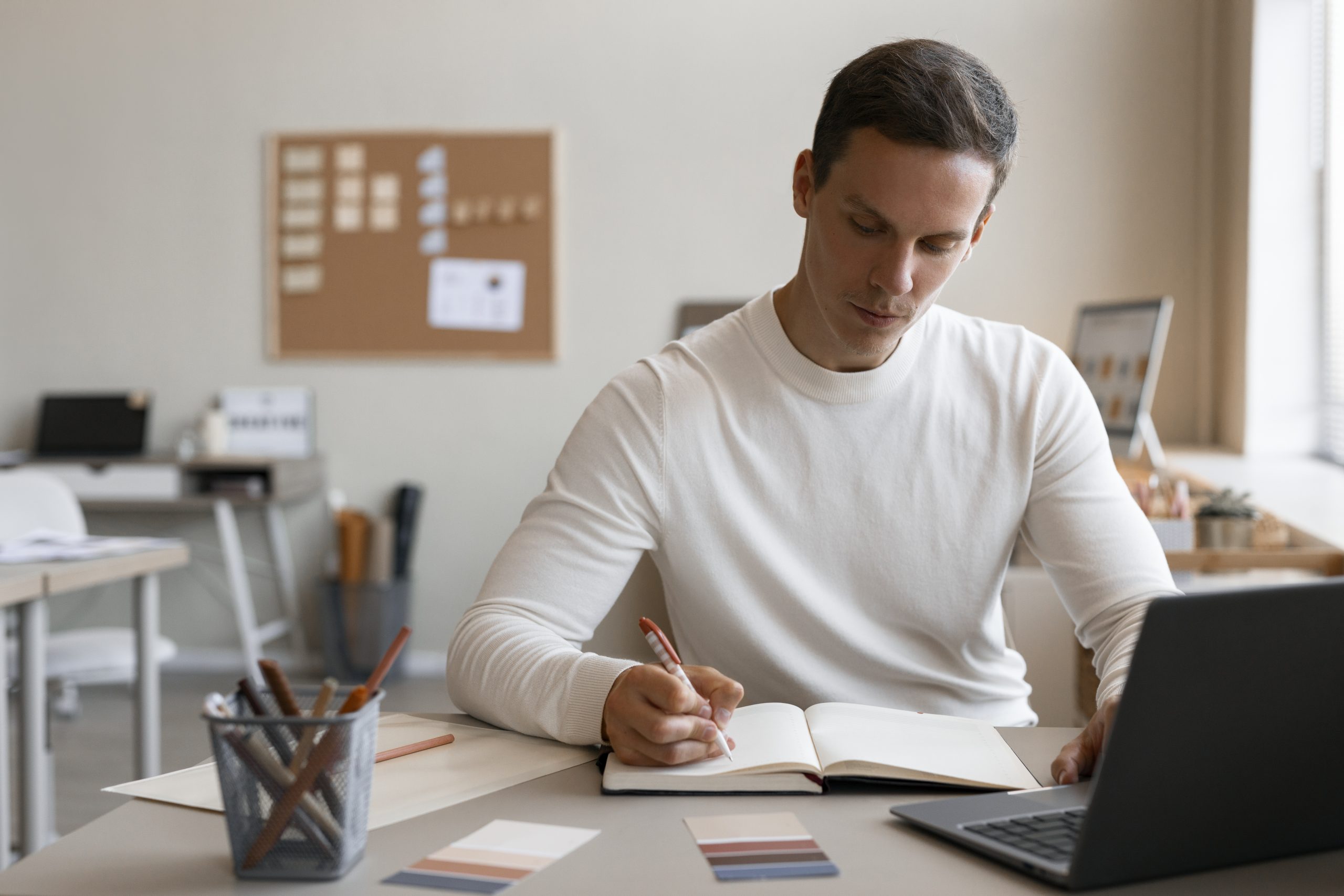 homem sentado com livros e computador sobre uma mesa concentrado estudando