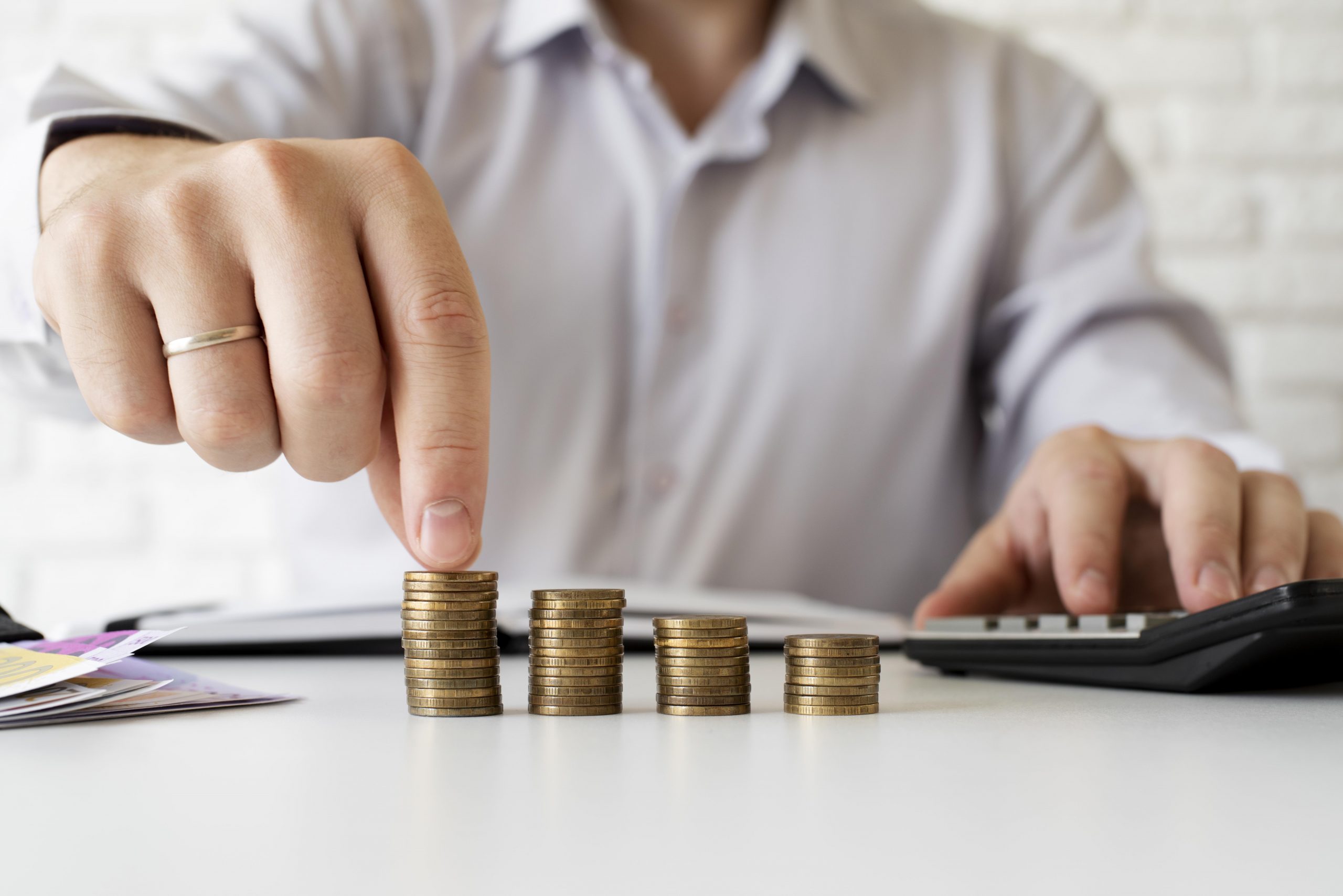 moedas sobre uma mesa em formato crescente e um homem posicionando as moedas