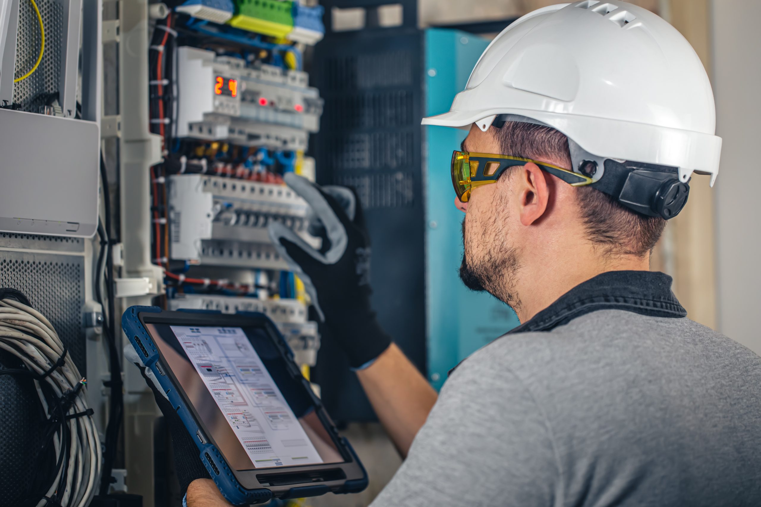 homem com equipamento de proteção mexendo em painel eletrônico