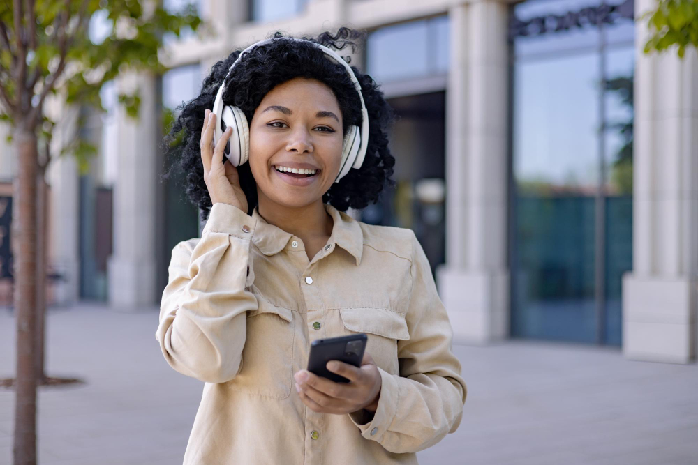 mulher andando na rua com fones nos ouvidos e celular na mão