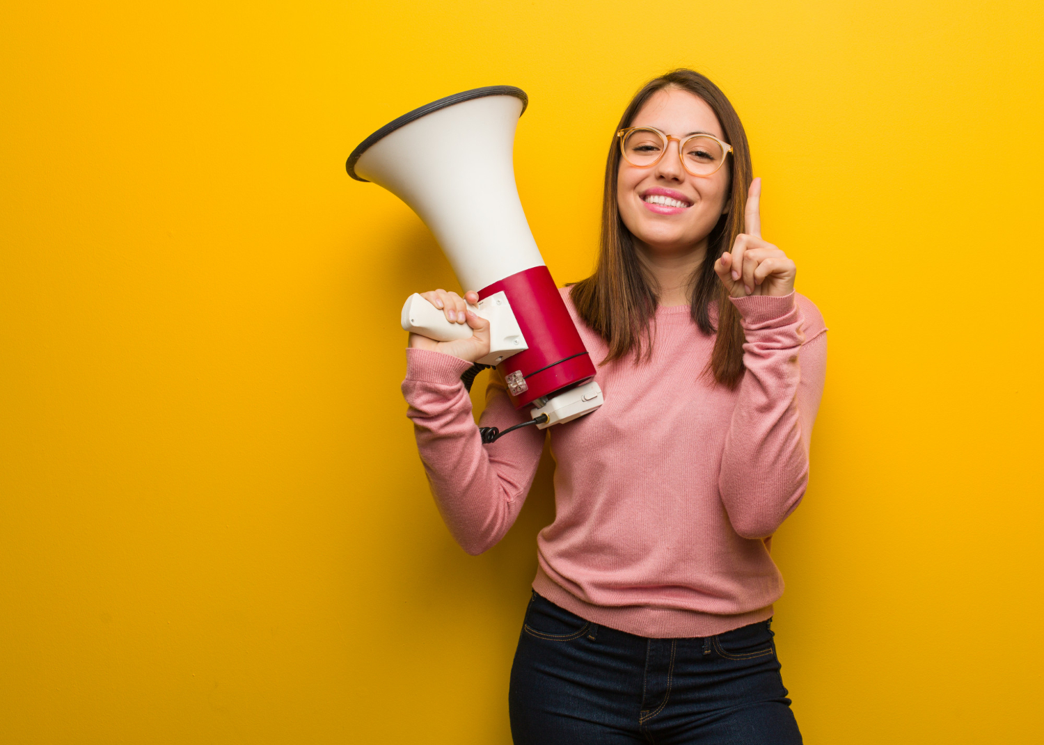 Mulher com um megafone em uma das mãos, com um sorriso no rosto.