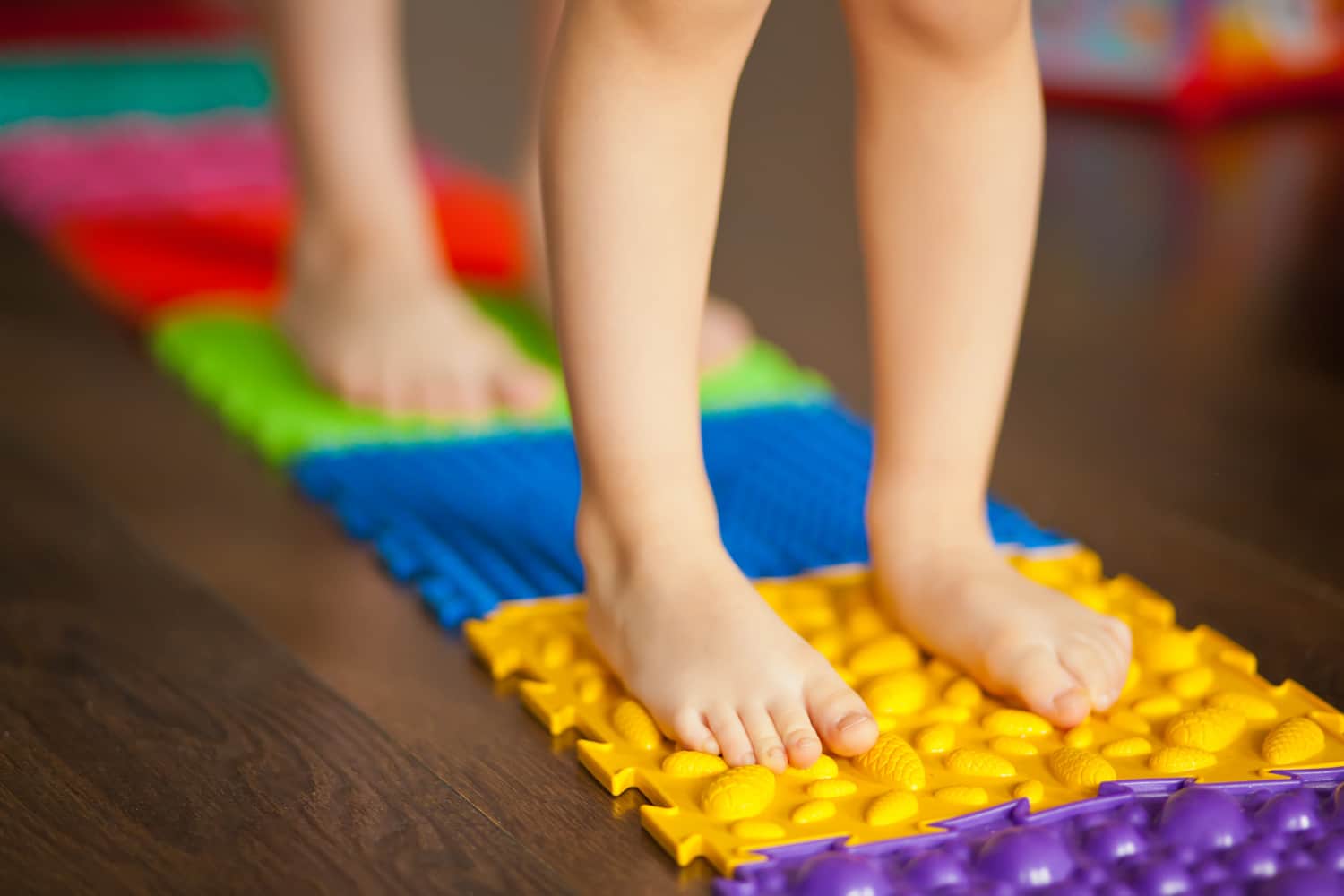 pés de crianças em cima de um tapete colorido com diferentes texturas