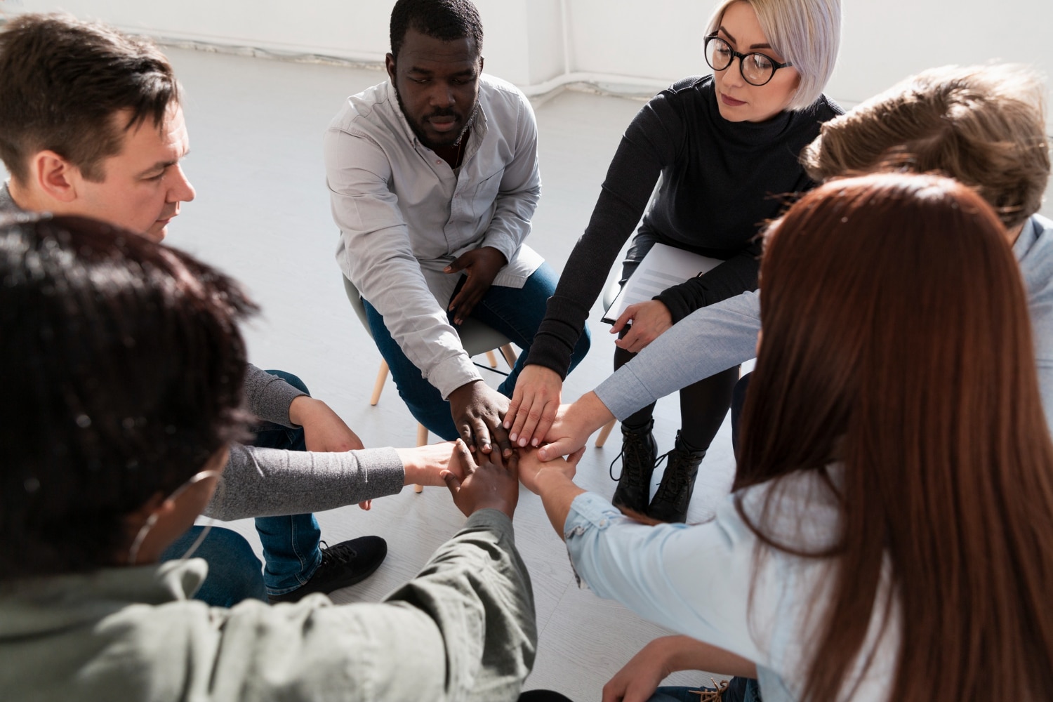 grupo de pessoas sentadas em uma roda dando as mãos ao centro, representando as habiliades interculturais
