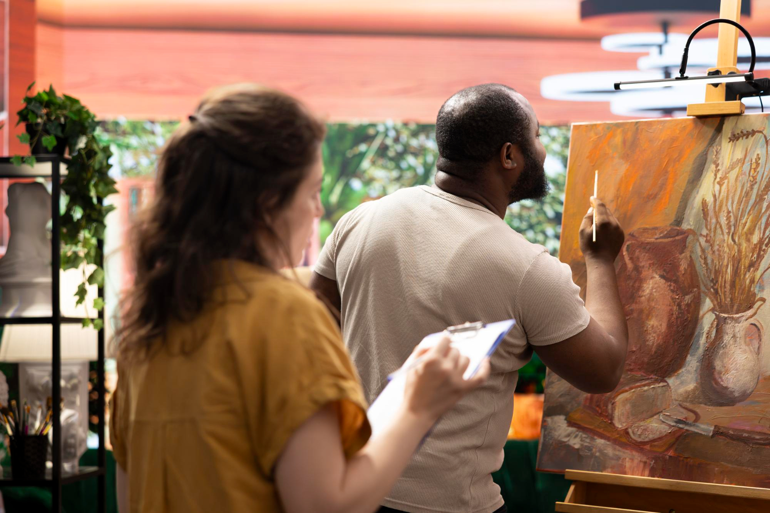 Mulher mestre pintor ensinando seu aprendiz a usar novas técnicas de pintura