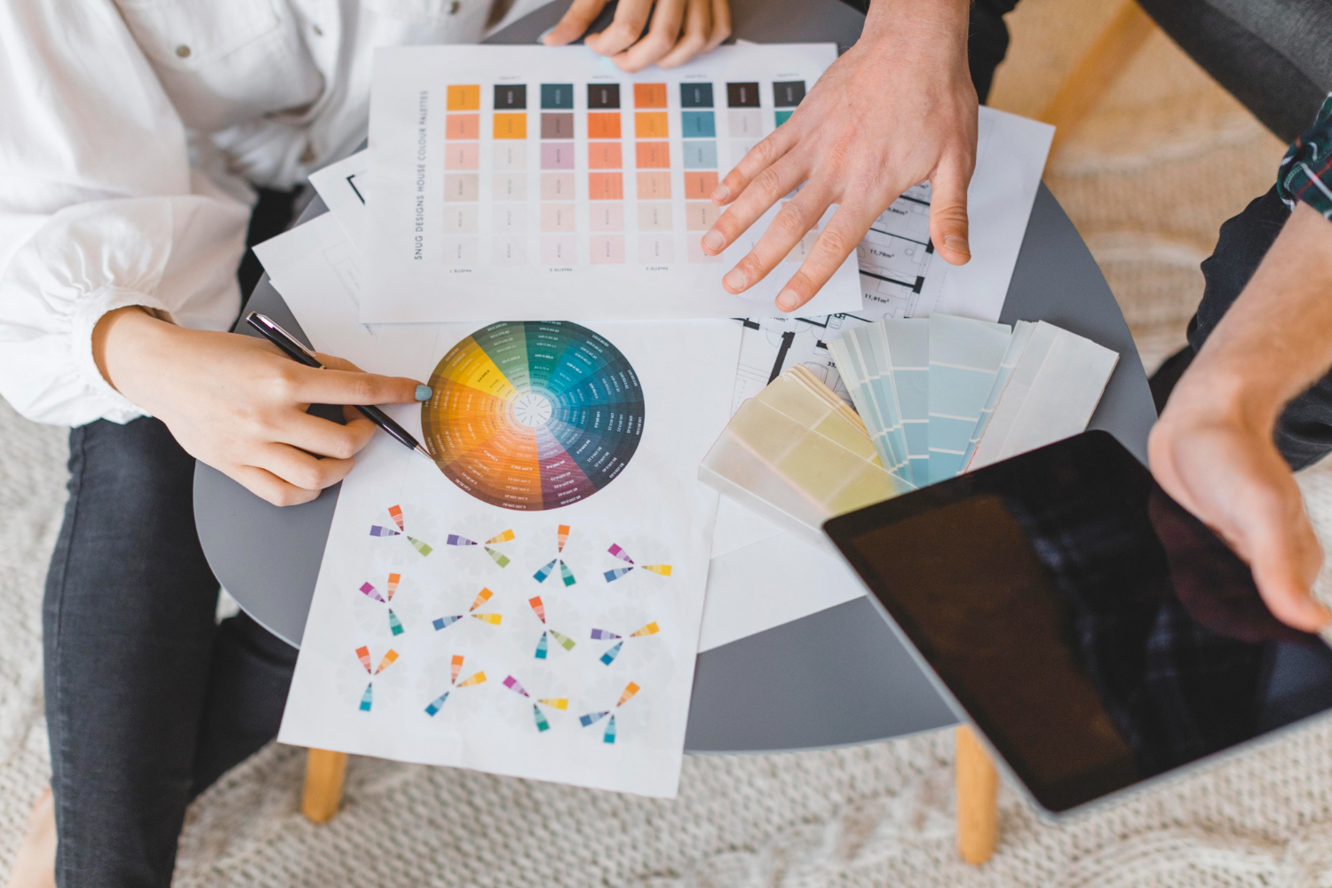 Casal fazendo planos para redecorar a casa, consultando diversas paletas de cores impressas